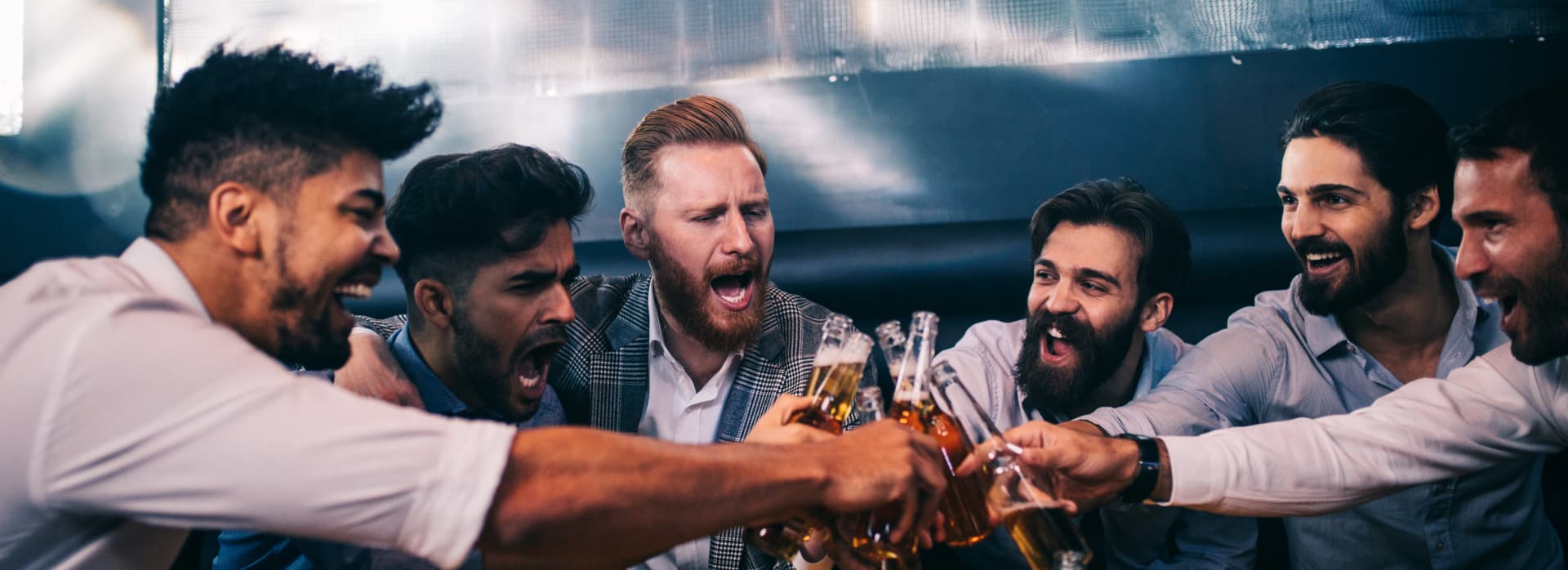 Group of young men toasting with beer at a nightclub